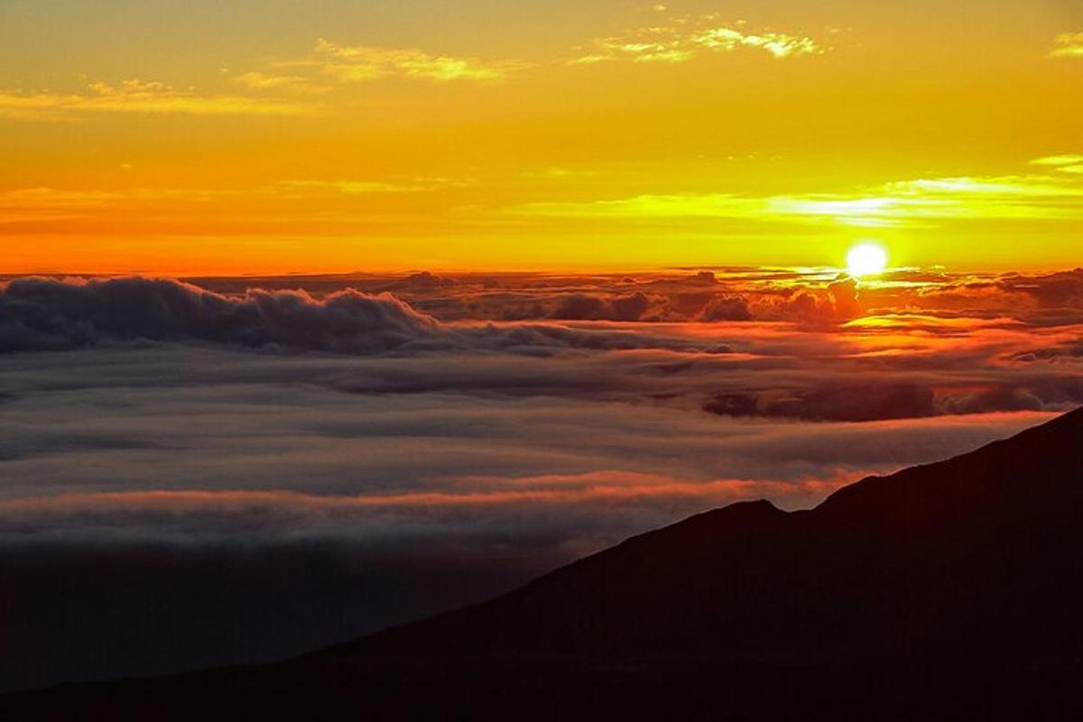 a view of the sun rising over a layer of clouds