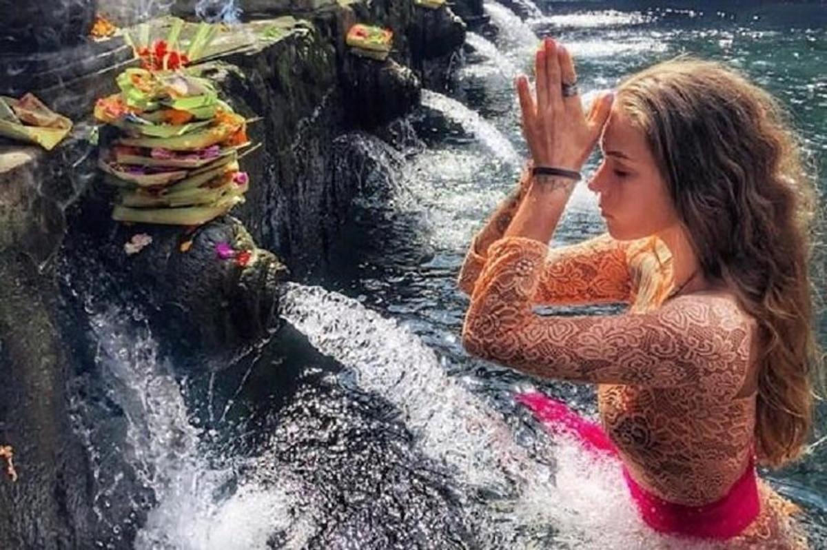 eine Frau, die im Wasser in der Nähe eines Wasserfalls steht