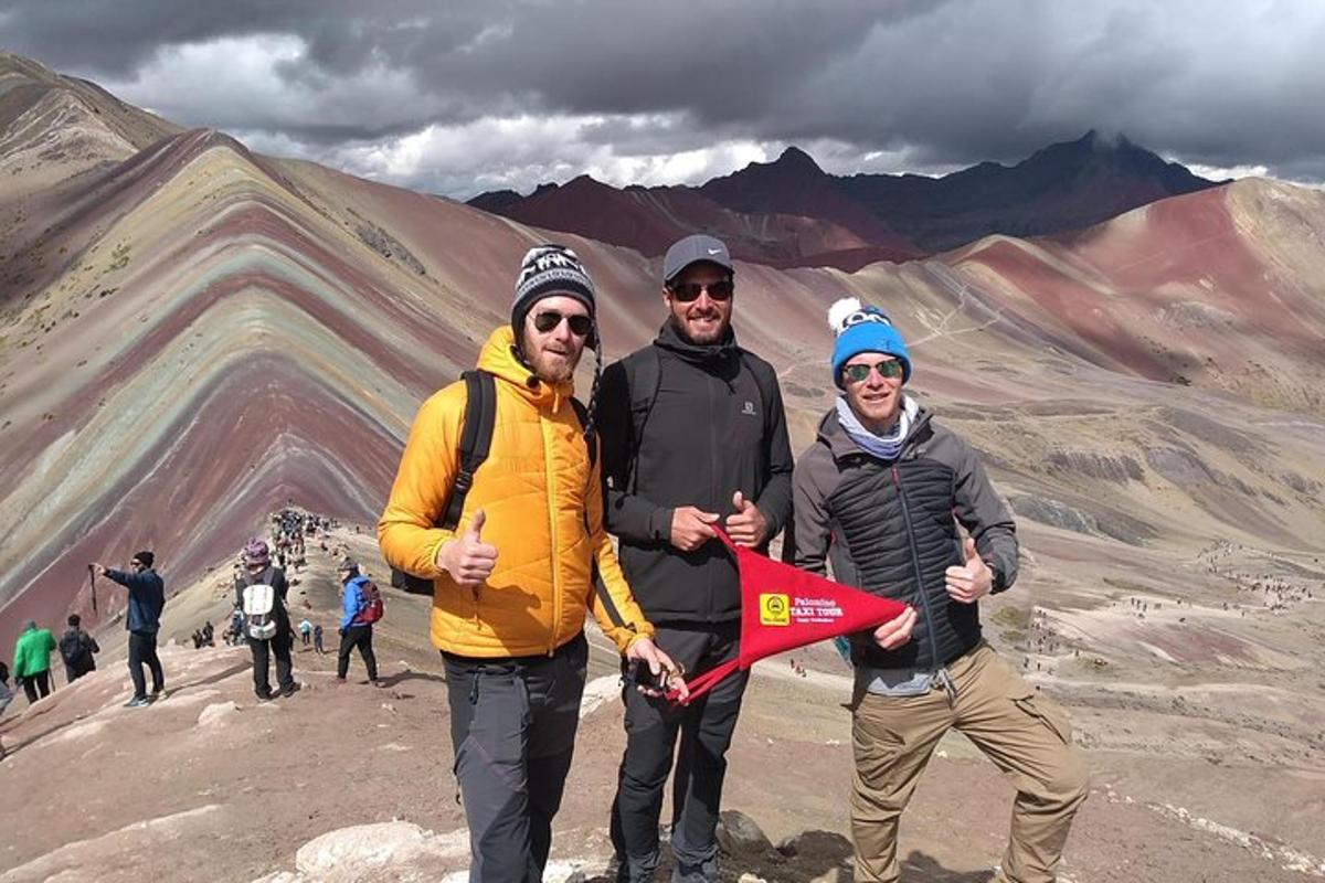 tre persone in piedi su una montagna che tengono un aquilone