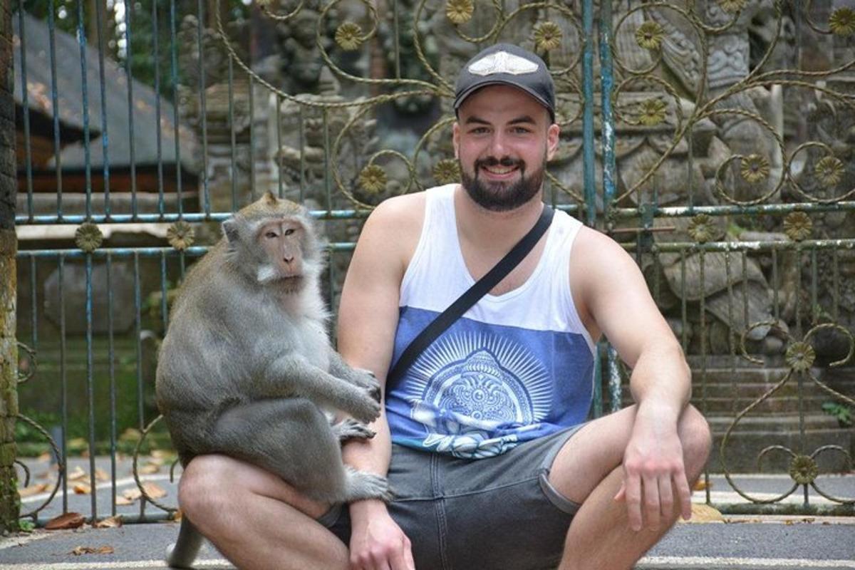 Un hombre sosteniendo un mono frente a una valla.