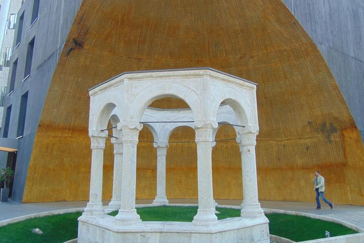 uma pessoa passando por uma grande escultura de um edifício
