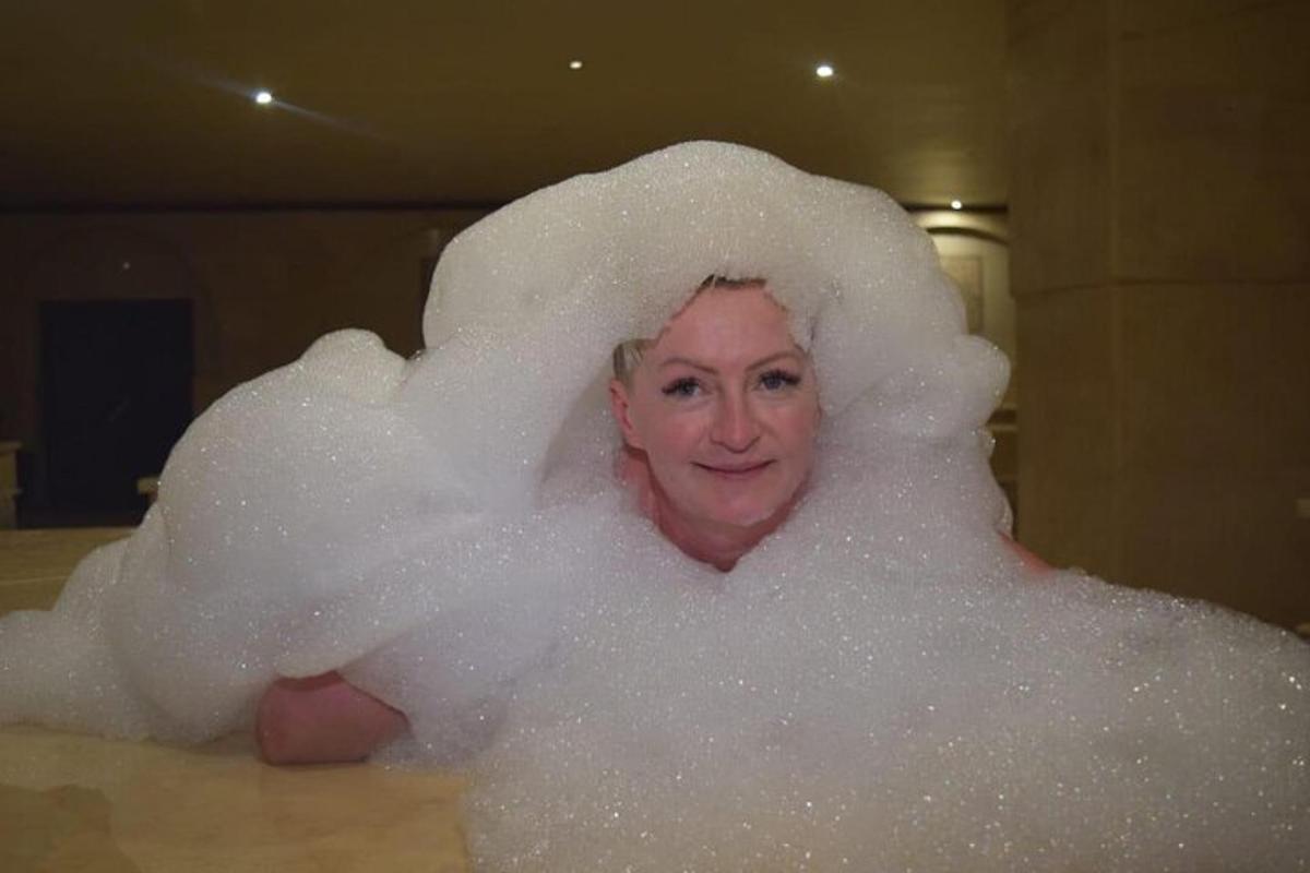 una donna in una vasca da bagno ricoperta di bolle
