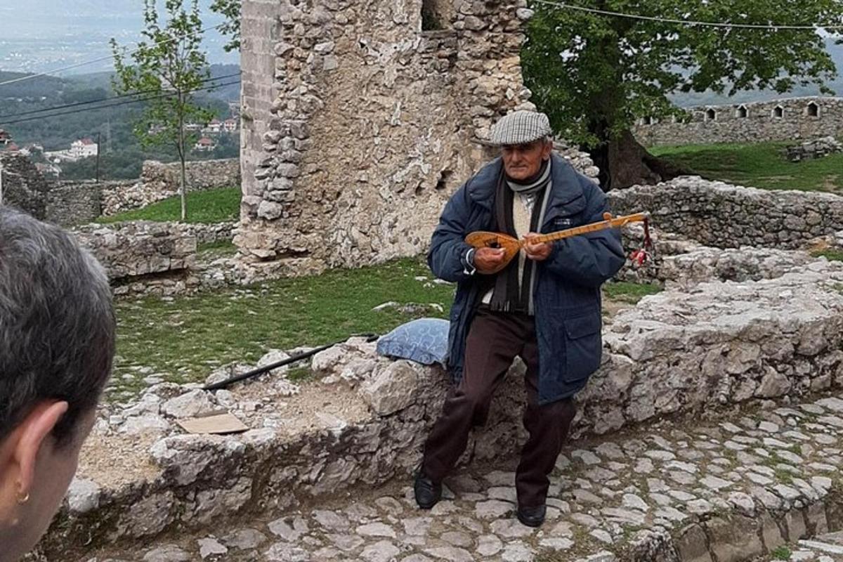muž stojící na kamenné zdi hrající na hudební nástroj