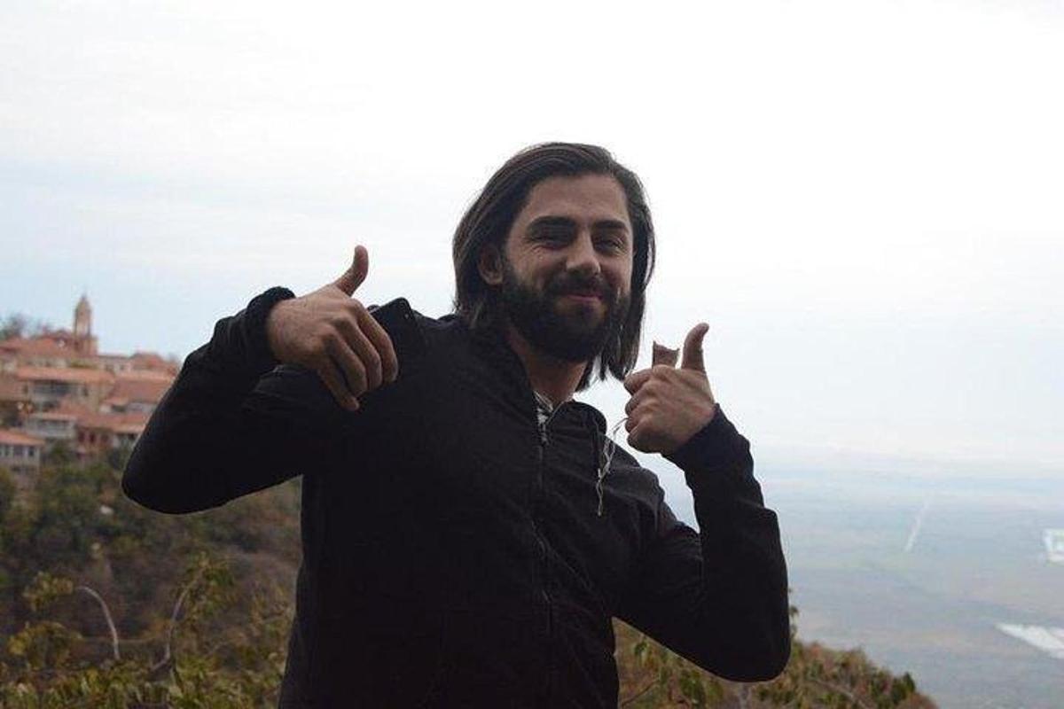 un uomo che fa il gesto del pollice in su mentre è in piedi su una montagna