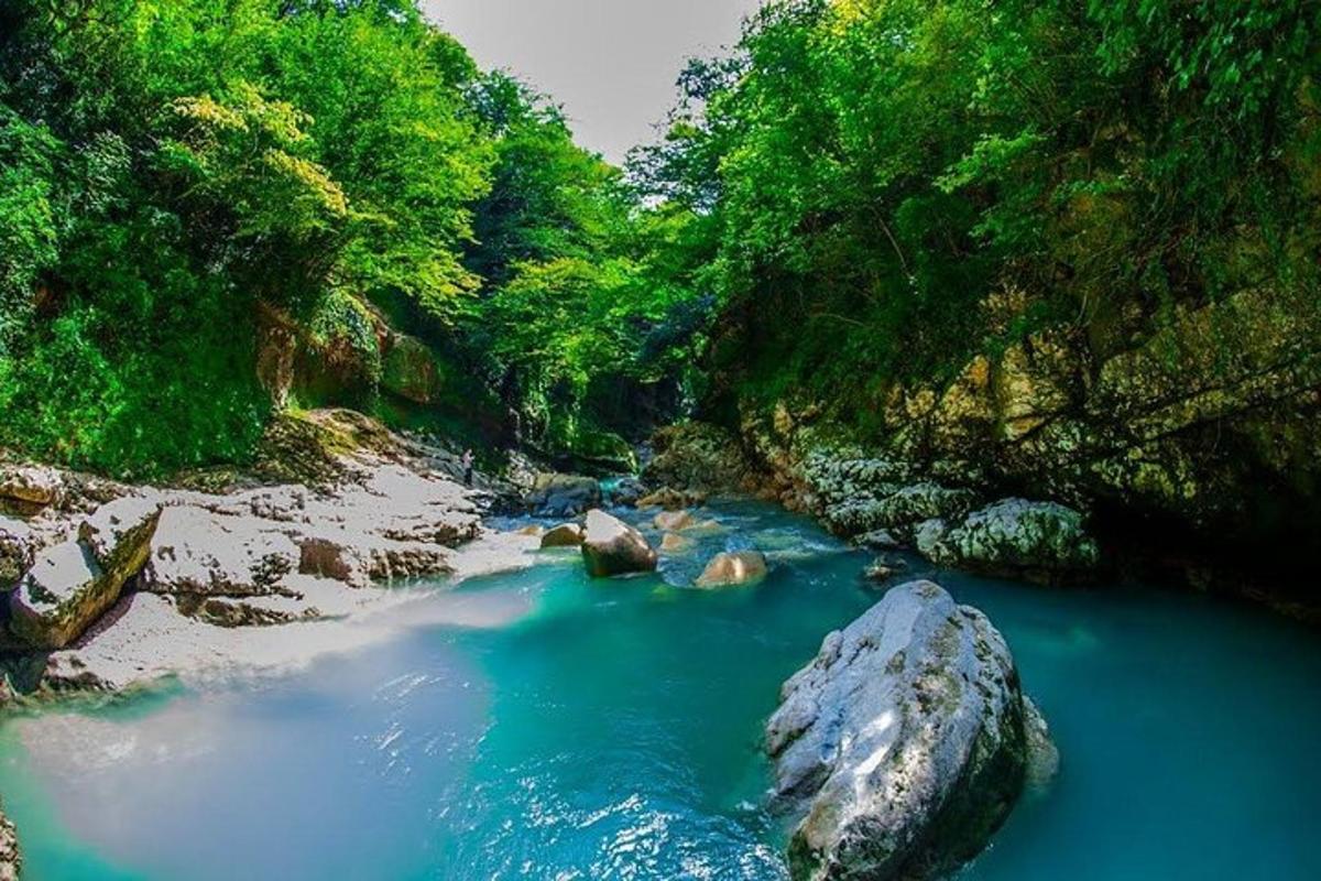 un fiume con acqua blu e rocce in una foresta