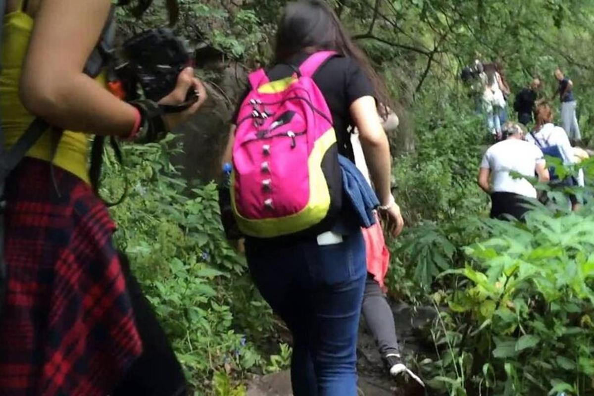 a woman walking down a trail with a pink backpack