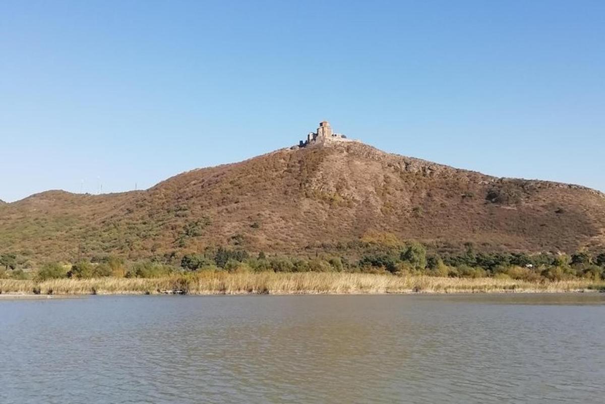 un turó amb una casa al cim al costat d'una massa d'aigua