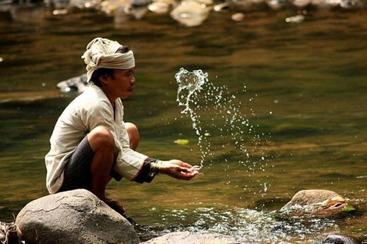 một người ngồi trên một tảng đá trong nước