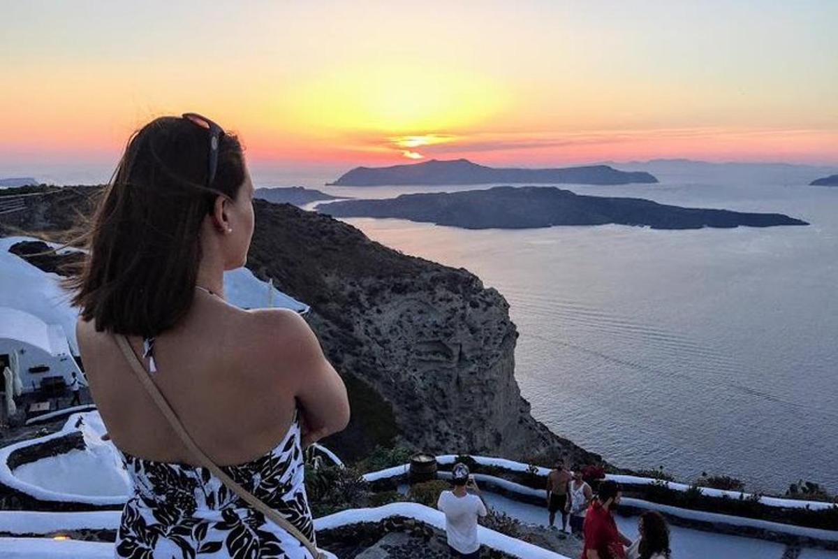 una donna in piedi in cima a una scogliera che guarda il tramonto