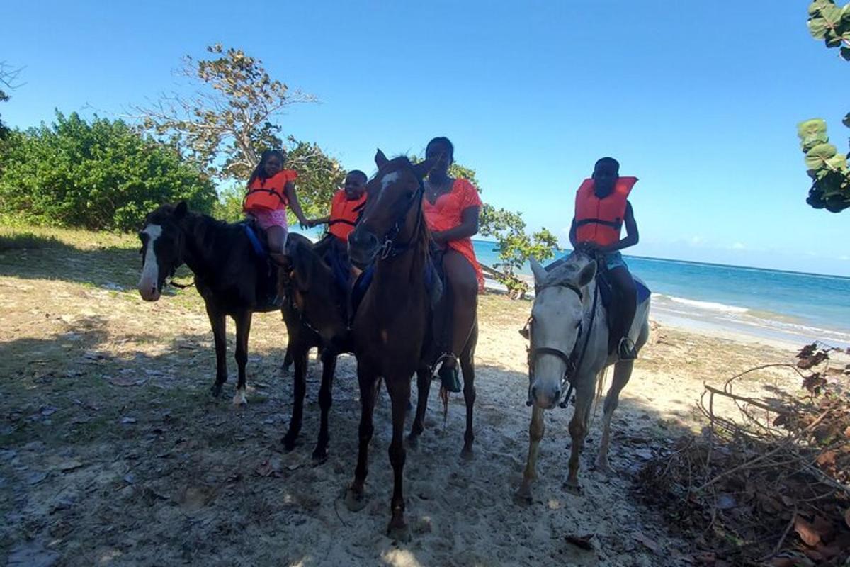 en gruppe mennesker som rir på hester på stranden