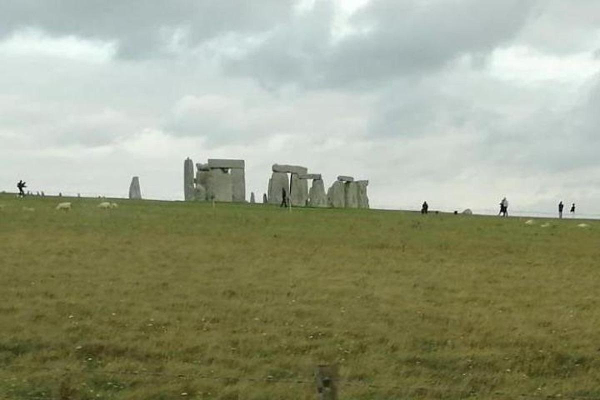 un gruppo di persone in piedi in un campo con Stonehenge