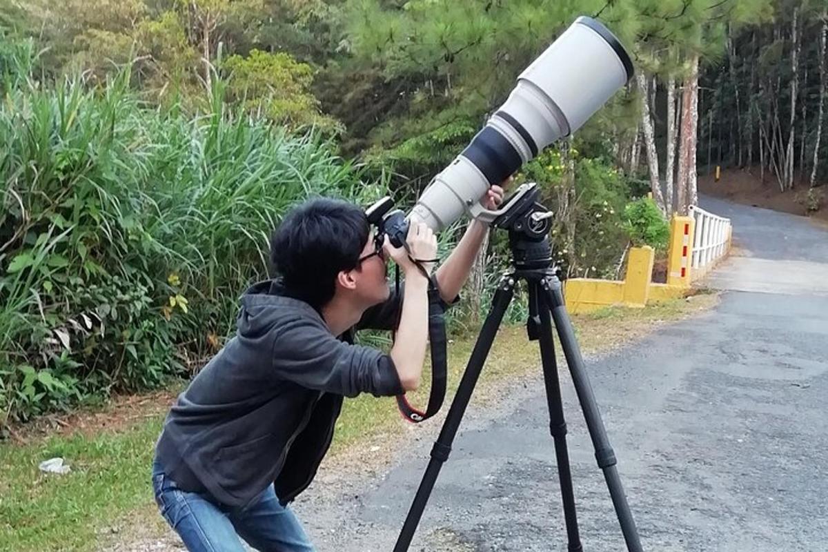 seorang pria sedang melihat melalui teleskop di atas tripod