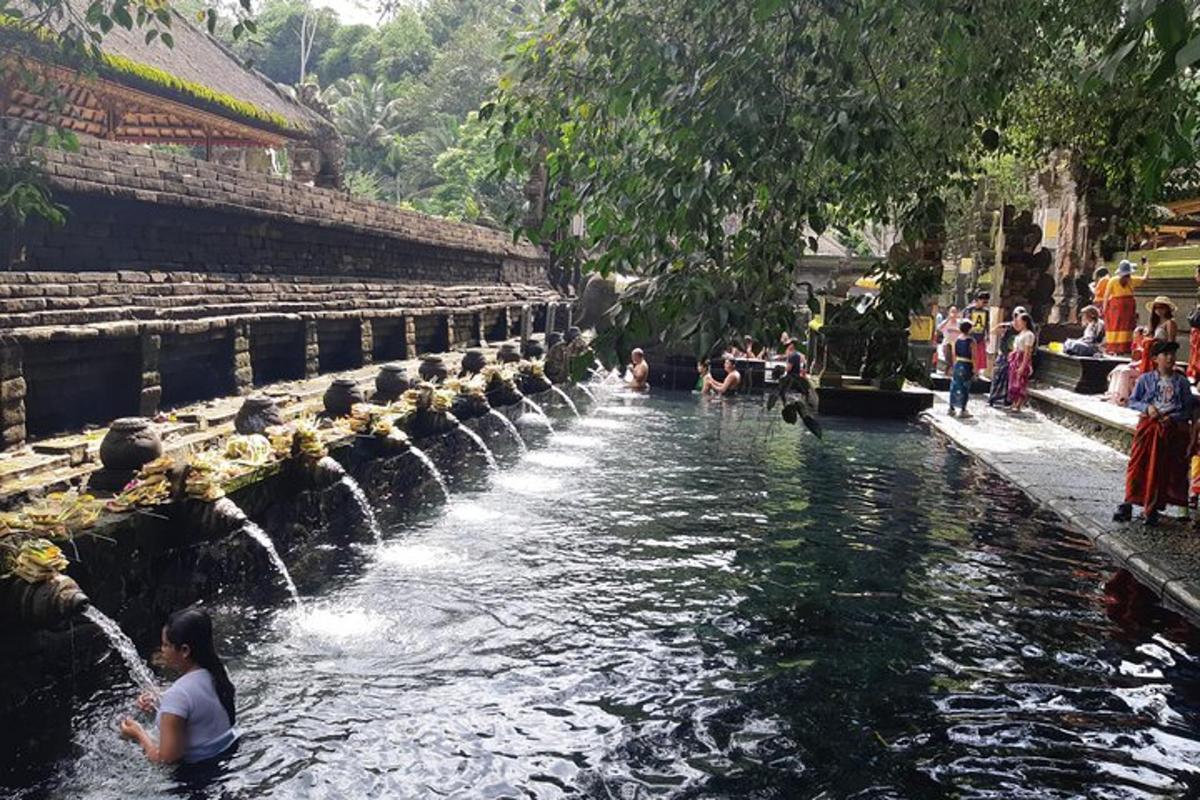 một người phụ nữ đang ngồi dưới nước cạnh một đài phun nước