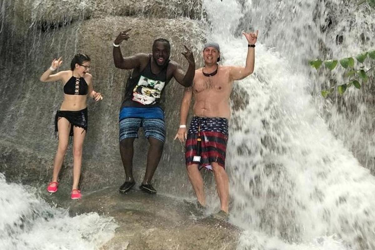 trois personnes debout devant une cascade