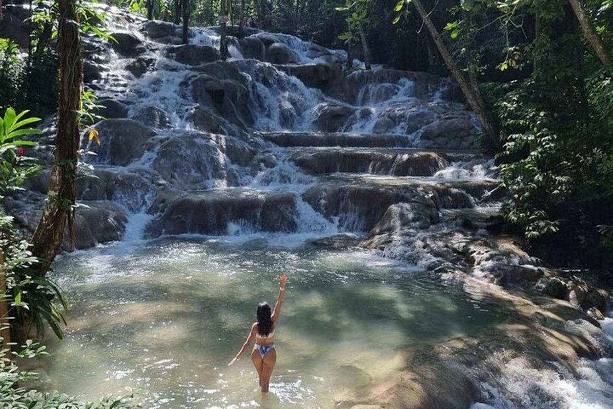kona í vatnspolli fyrir framan foss
