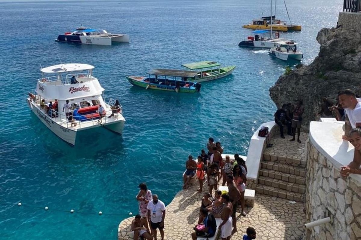um grupo de pessoas em pé na escada olhando para os barcos na água