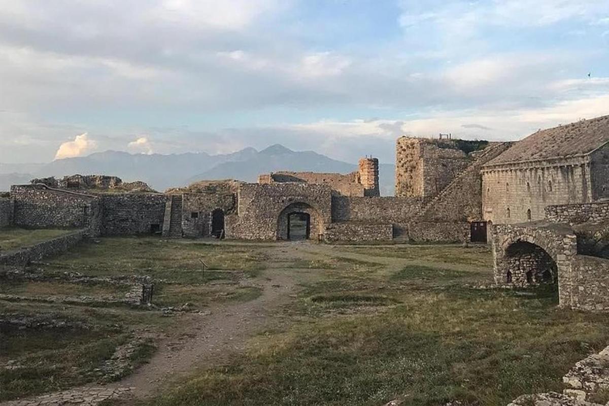 um prédio antigo em um campo com montanhas ao fundo
