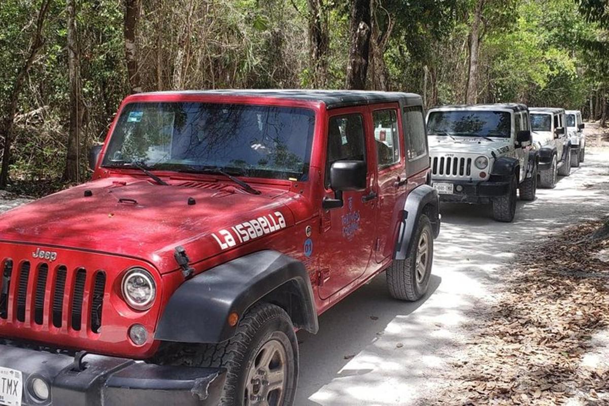 một chiếc xe jeep màu đỏ đỗ trên một con đường đất