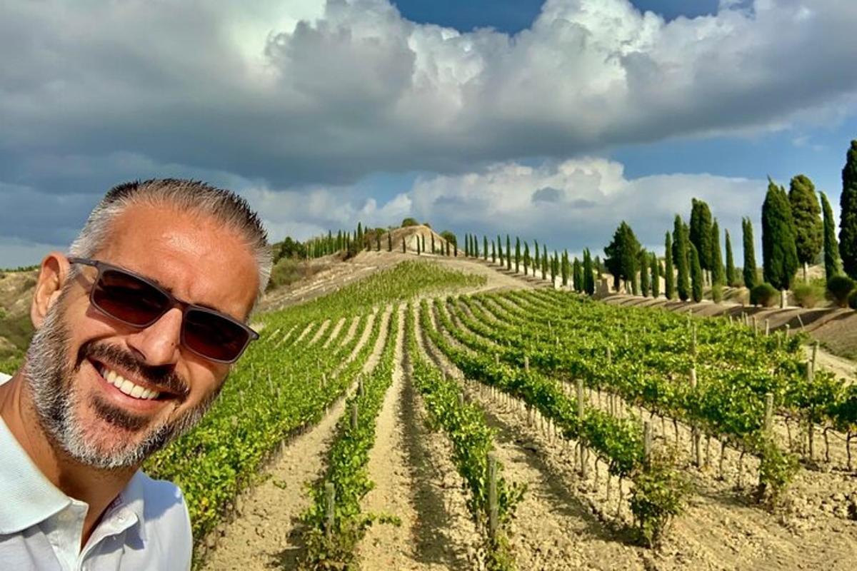 muž se slunečními brýlemi stojící před vinicí