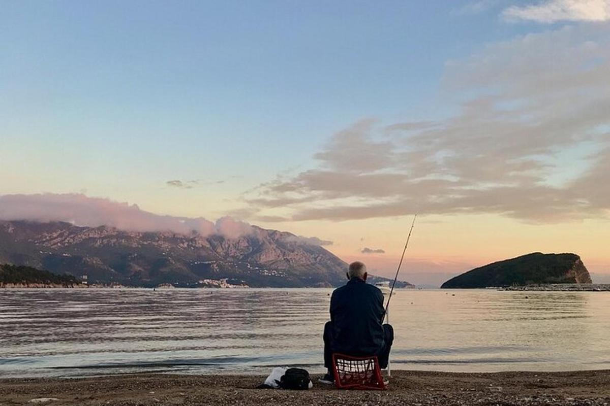 moški sedi na plaži in lovi ribe v vodi
