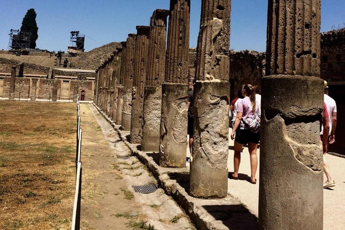 Una mujer de pie junto a una fila de pilares.