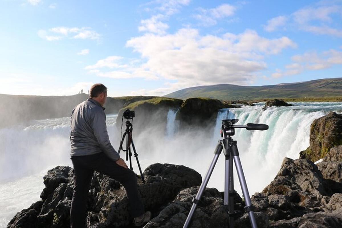 un homme avec un appareil photo à côté d'une cascade