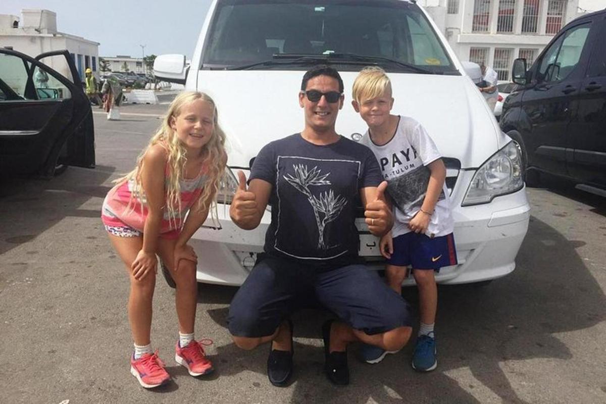Ένας άντρας και δύο παιδιά στέκονται μπροστά από ένα βαν