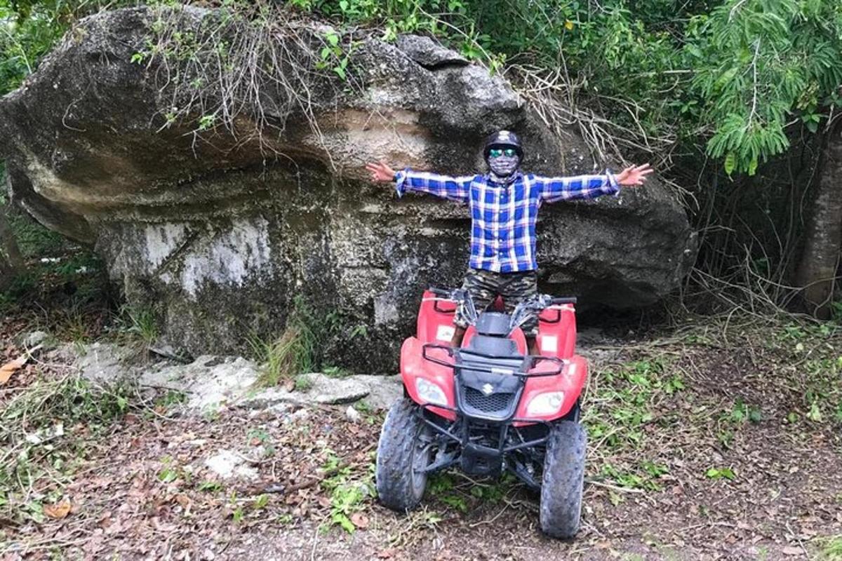 muž na čtyřkolce před skálou