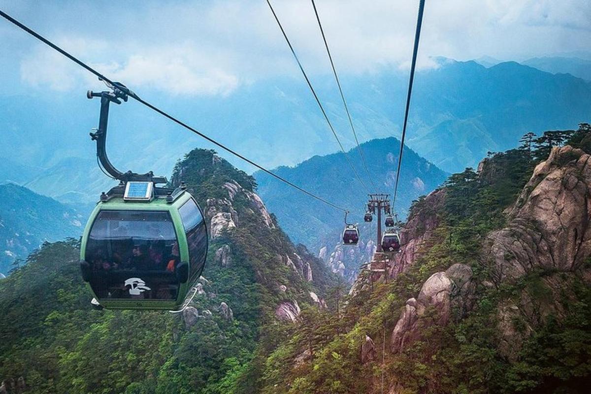a gondola flying over a mountain with people on it