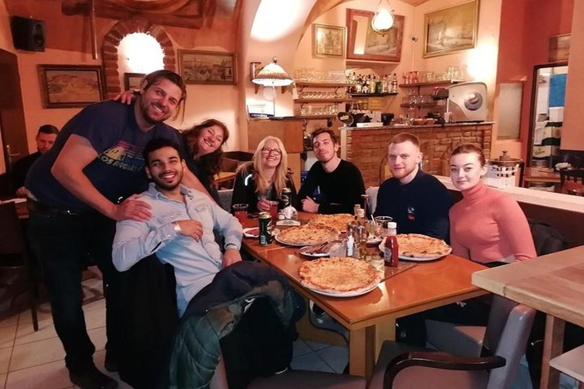 un grup de oameni așezați în jurul unei mese mâncând pizza