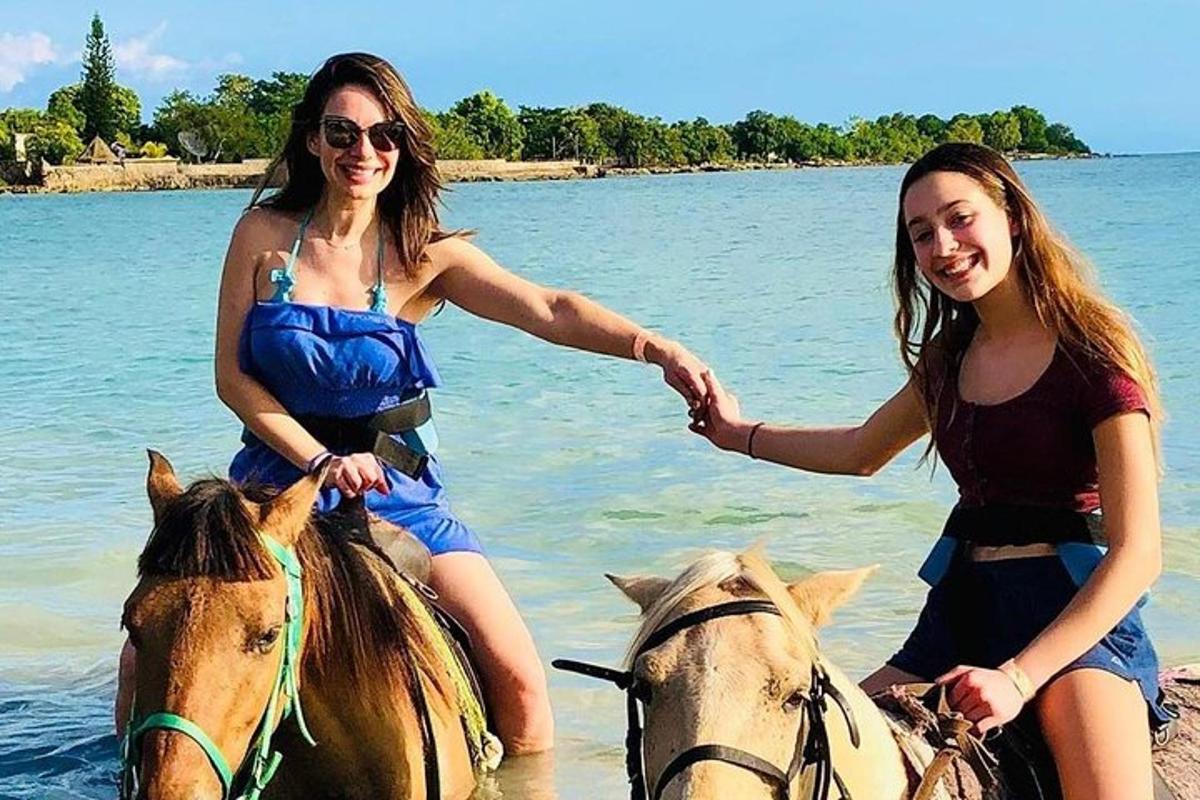 due donne stanno cavalcando cavalli nell'acqua