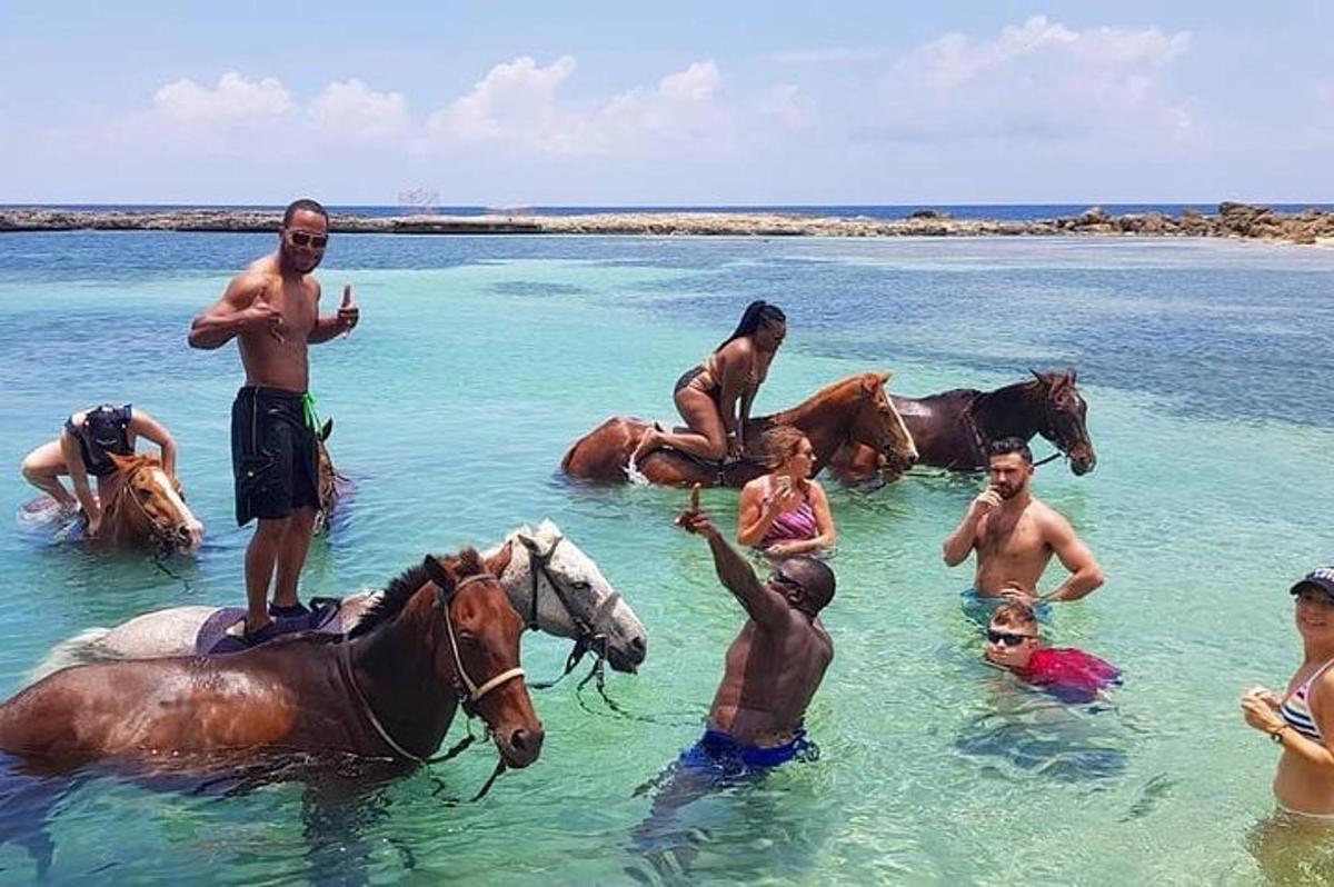un gruppo di persone in acqua con i cavalli