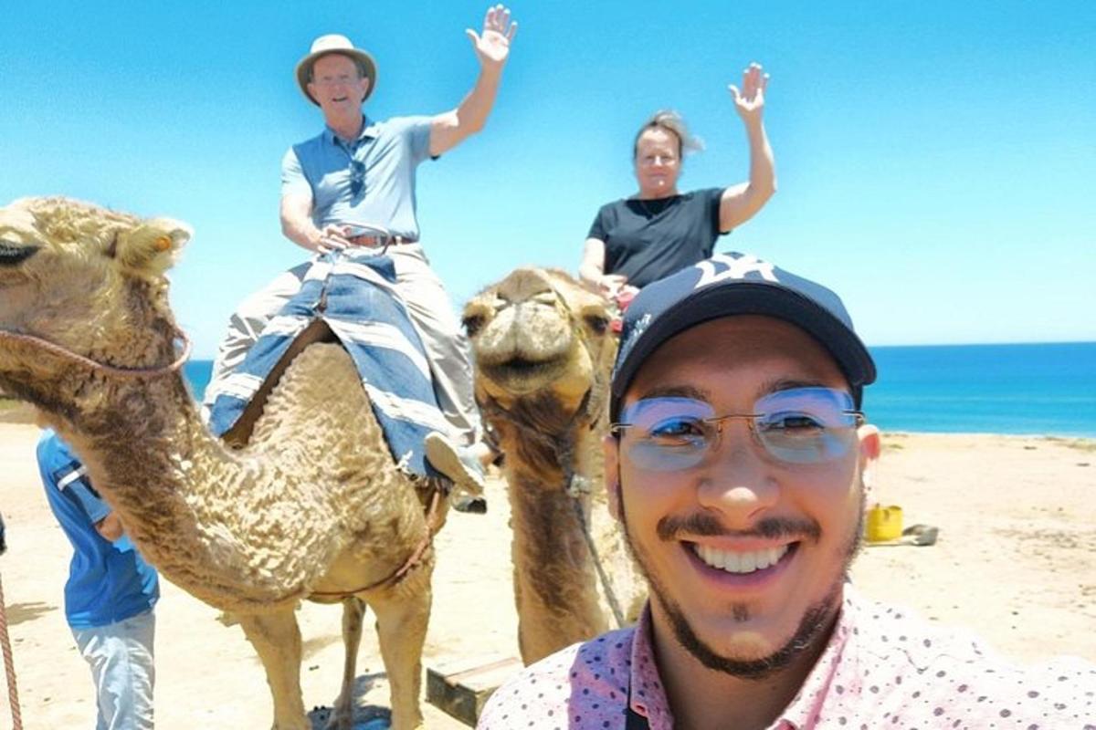 dua orang menaiki unta di pantai