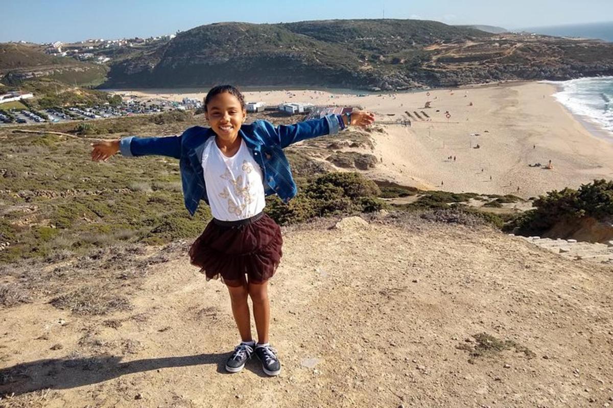una ragazza in piedi in cima a una collina vicino a una spiaggia