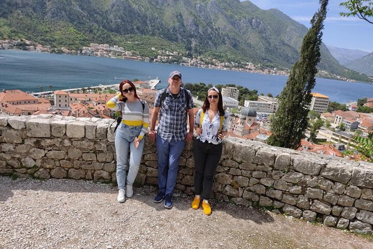 Tres personas de pie junto a un muro de piedra