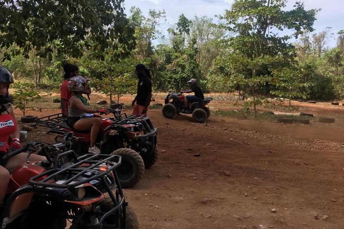 Un grupo de personas conduciendo vehículos todo terreno por un camino de tierra.