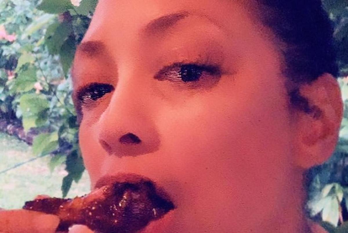 en kvinne som spiser et pizzastykke foran ansiktet sitt