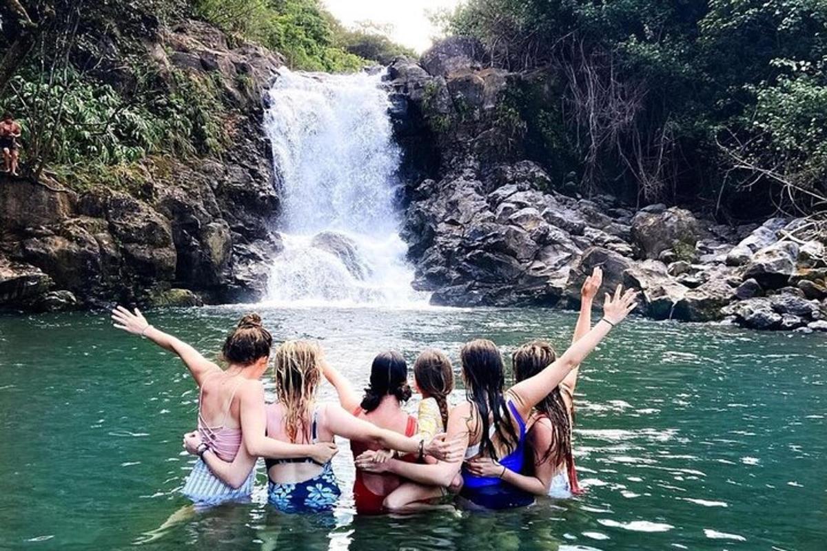 Un grupo de chicas en el agua frente a una cascada.