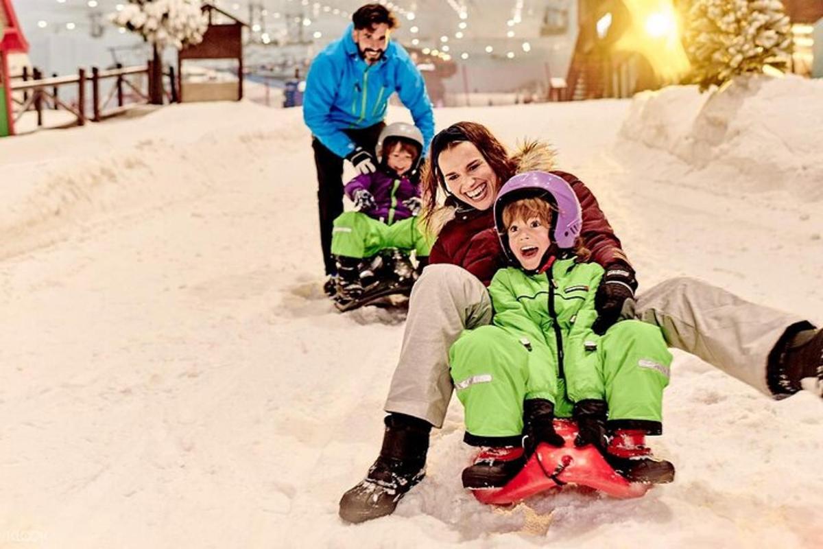 a woman and two children riding on a snowledge