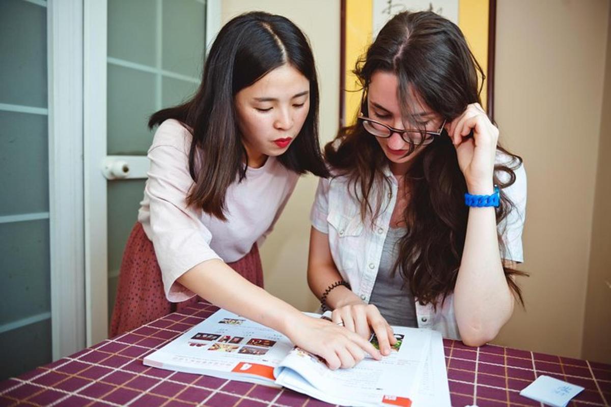 hai người phụ nữ đang nhìn vào một tờ giấy trên bàn
