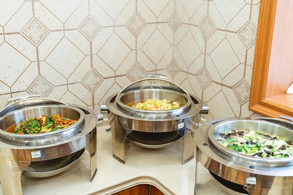 three large metal pans filled with different types of food