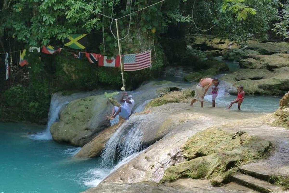 um grupo de pessoas em pé sobre rochas perto de uma cachoeira