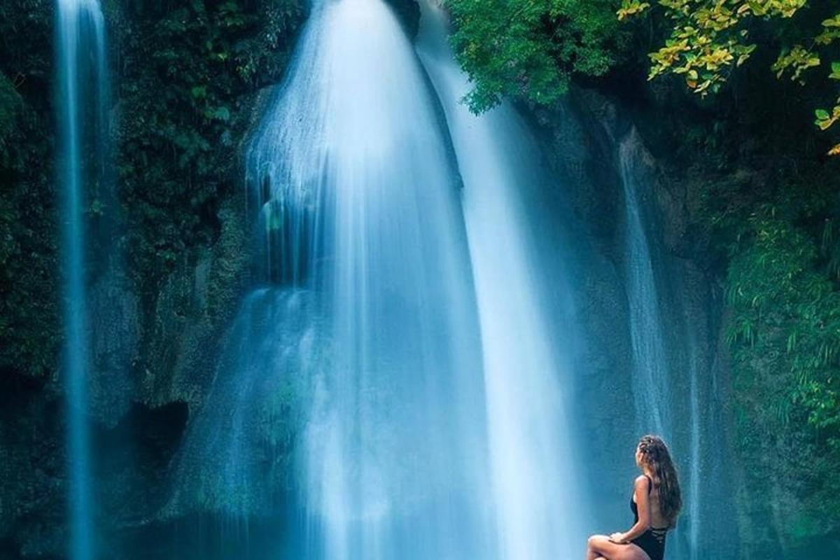 uma mulher sentada em frente a uma cachoeira