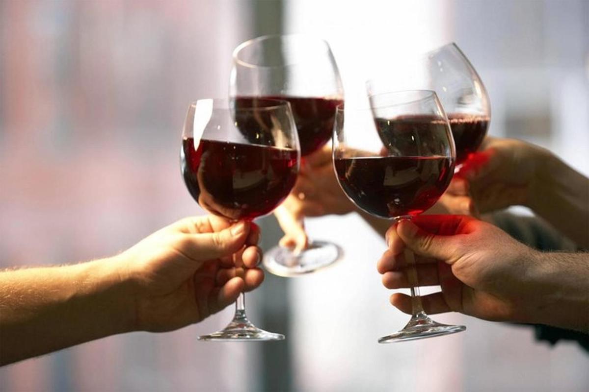 tres persones sostenint copes de vi negre