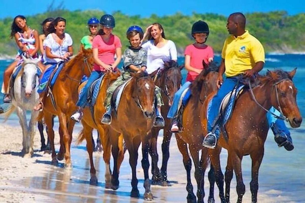 um grupo de pessoas andando a cavalo na praia