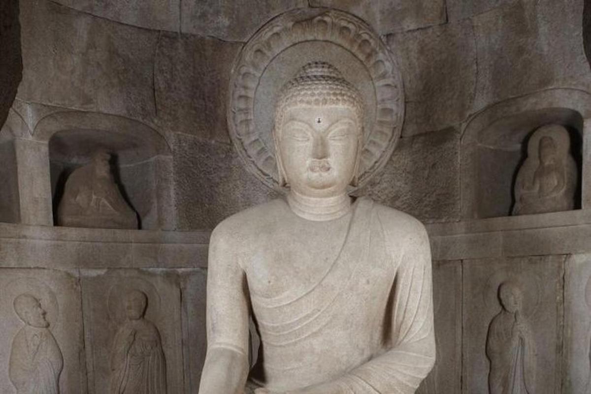 una statua seduta davanti a un muro