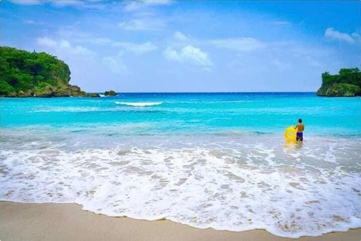 muž stojící v oceánu se žlutým surfovacím prknem
