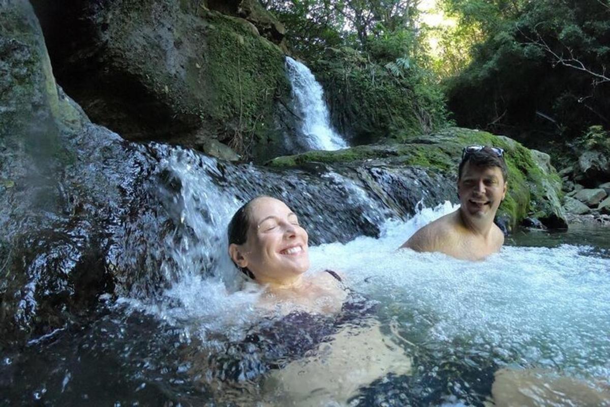 two men are swimming in a waterfall