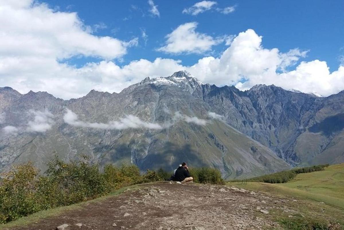 un uomo seduto in cima a una collina che guarda una montagna