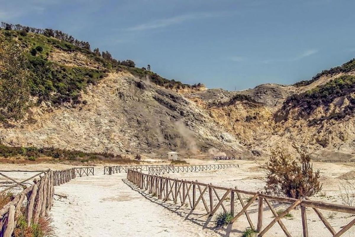 una tanca de fusta en un turó de terra amb una muntanya